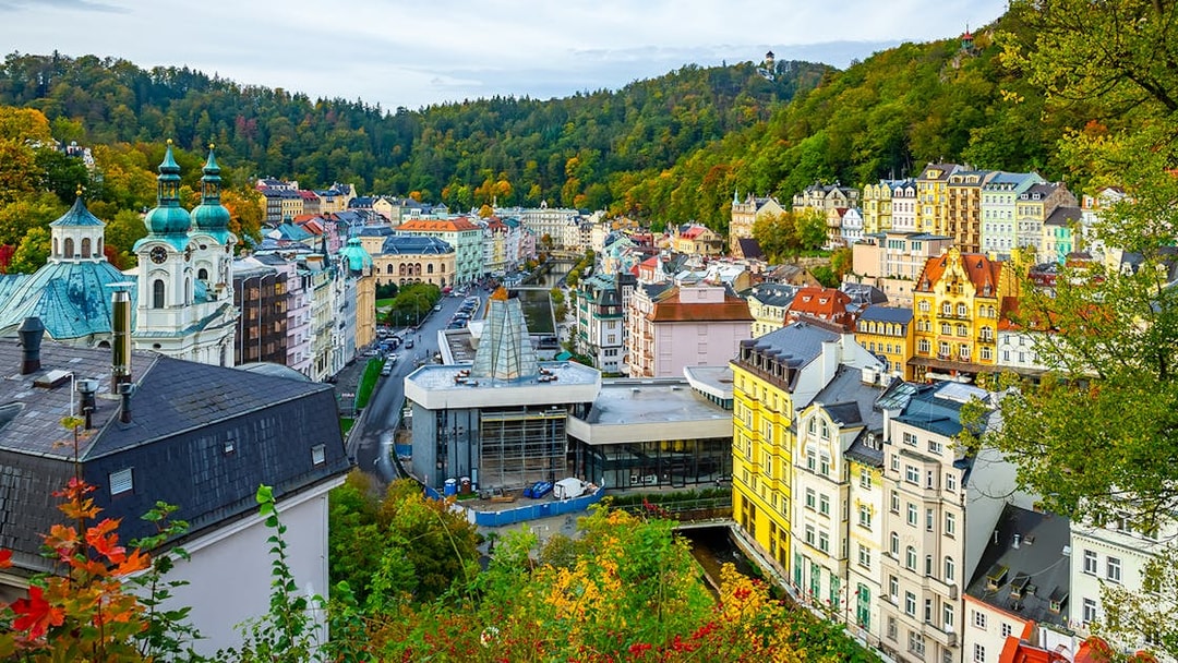 Karlovy Vary cityscape with colorful buildings and forested hills, view from Watchtower Diana.