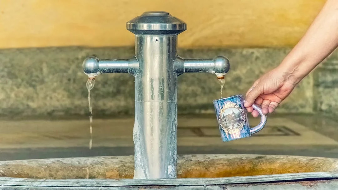 Filling a mug with mineral water from a spring in Karlovy Vary, Czech Republic.