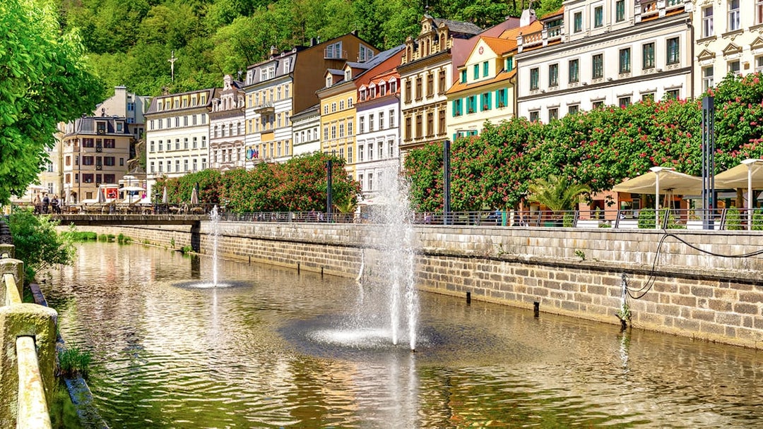 Karlovy Vary riverside with colorful buildings and fountains, Czech Republic.
