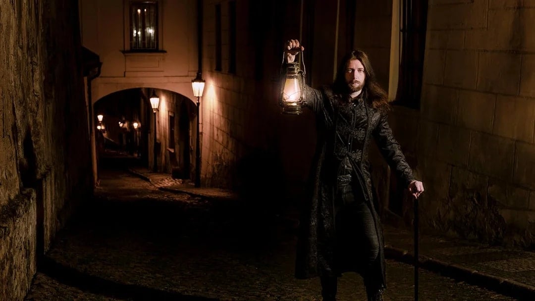Man holding lantern in dark alley during Prague's Old Town ghost tour.