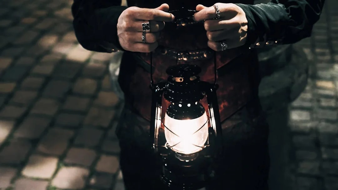 Person holding a lantern on cobblestone street during Prague's Old Town ghost tour.
