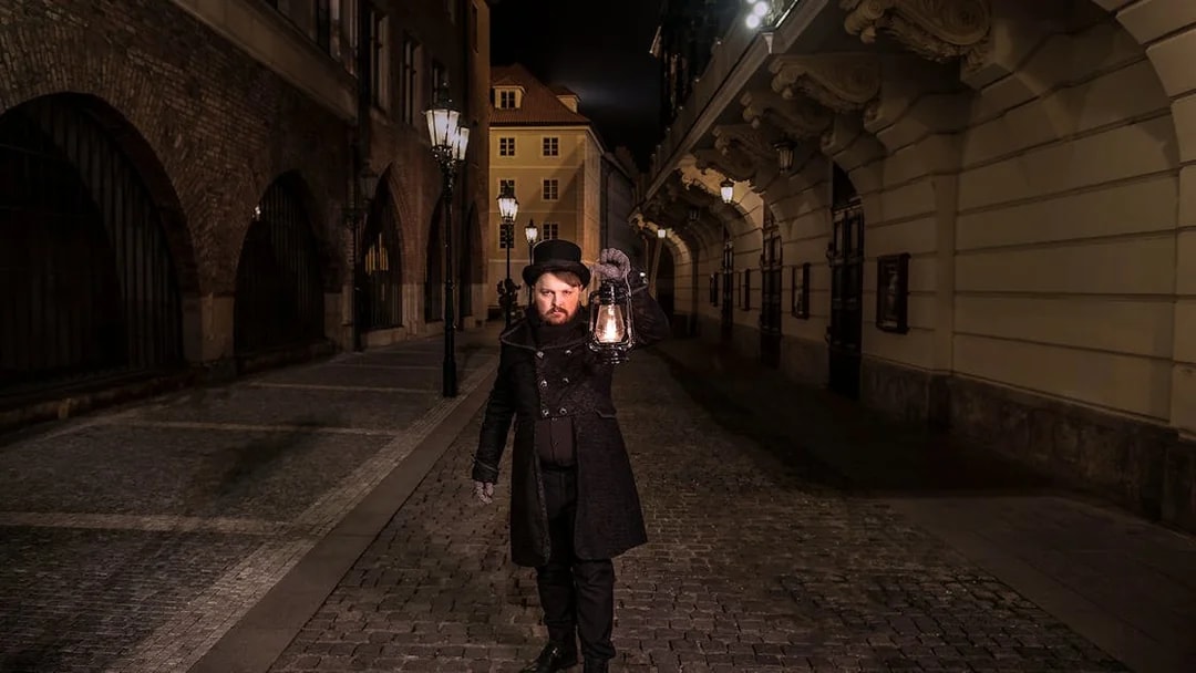 Guide holding lantern on cobblestone street during Prague Old Town ghost tour.