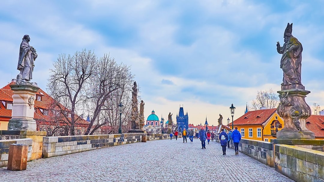 Tour group crossing Charles Bridge towards Prague Castle with Old Town in the background during Christmas.