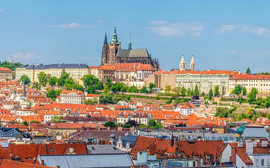 Aerial view of Prague's old town rooftops with the castle complex in the background.