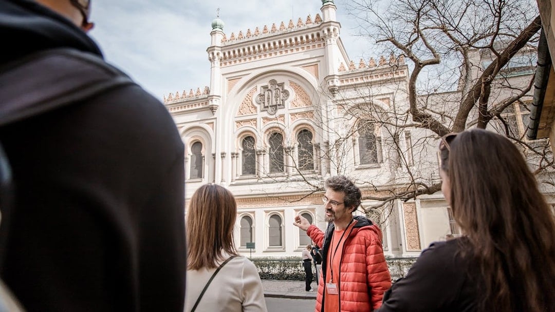 Tour guide explaining the Spanish Synagogue to visitors in Prague's Jewish Ghetto.