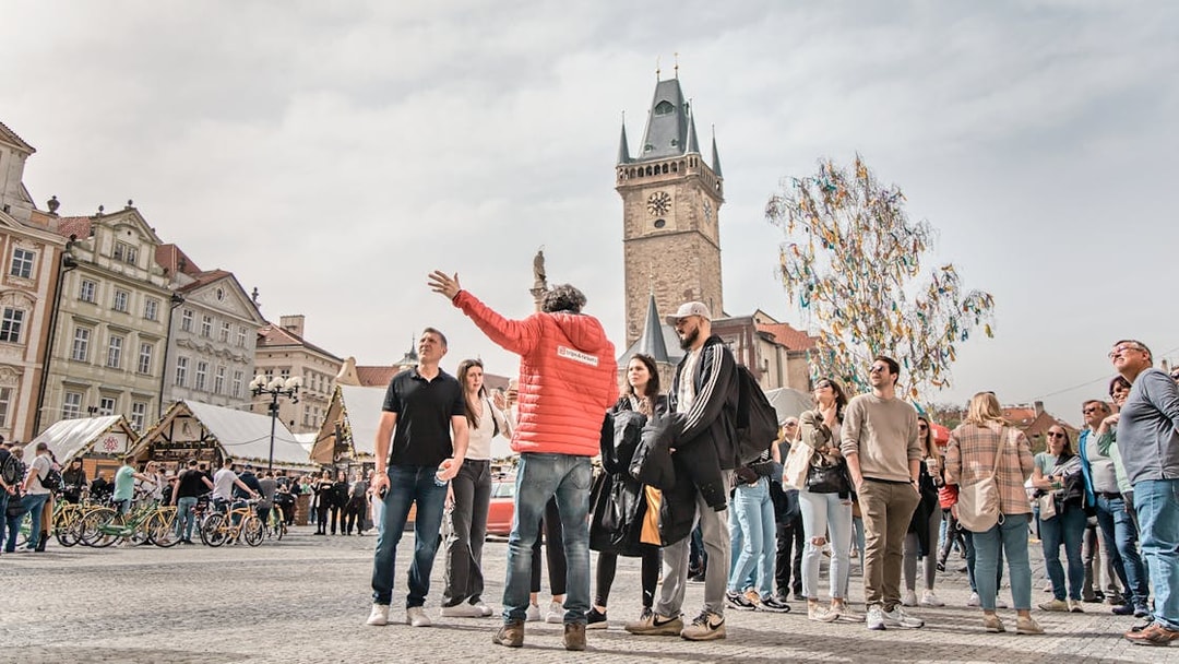 Tour guide leading a group in Prague's Old Town Square near the Astronomical Clock Tower.