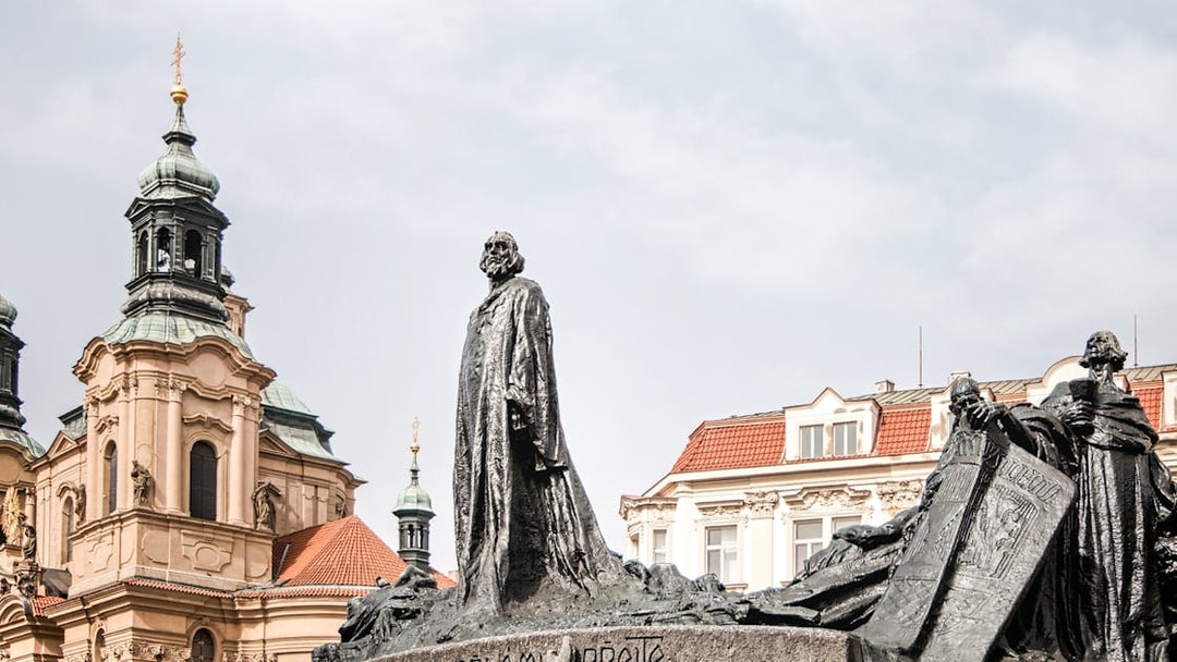 Statue of Jan Hus in Prague's Old Town Square with church in background.