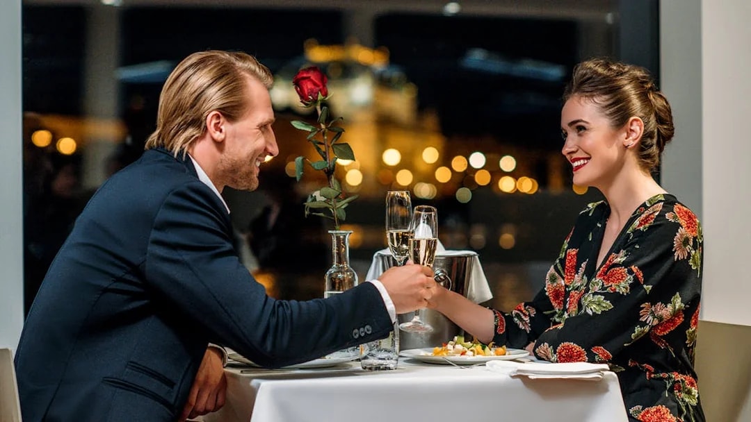 Couple enjoying a romantic dinner cruise in Prague with city lights in the background.
