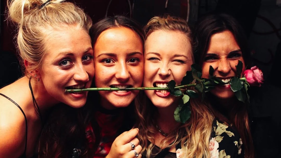 Group enjoying Prague pub crawl with rose in mouth.