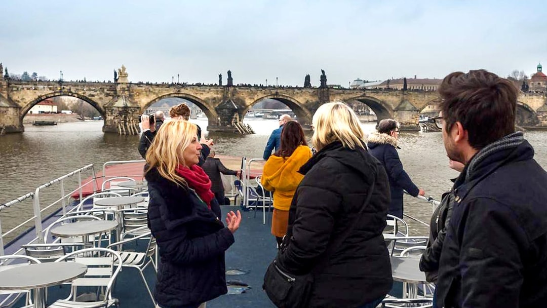 Prague boat cruise with tourists viewing Charles Bridge.