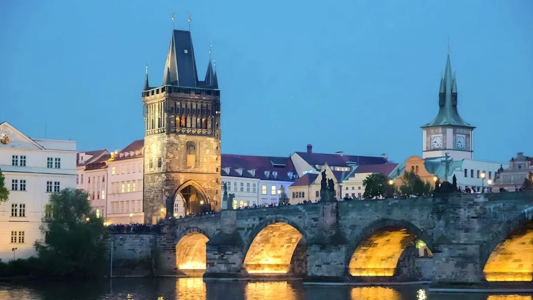 Charles Bridge illuminated at dusk in Prague, ideal for an evening dinner cruise with live music.