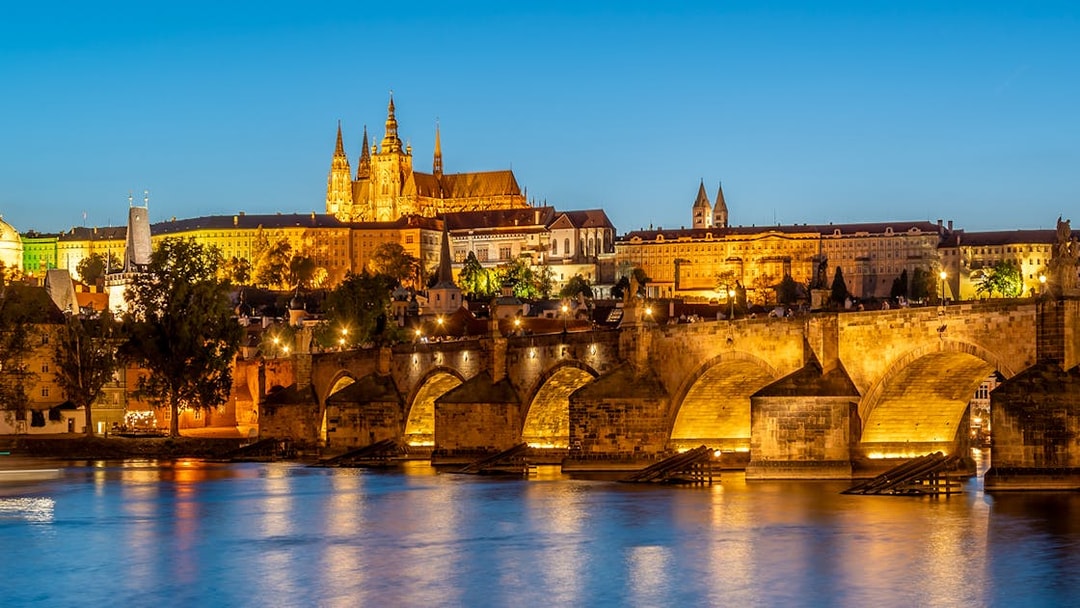 Prague Castle and Charles Bridge illuminated at night during an evening dinner cruise.