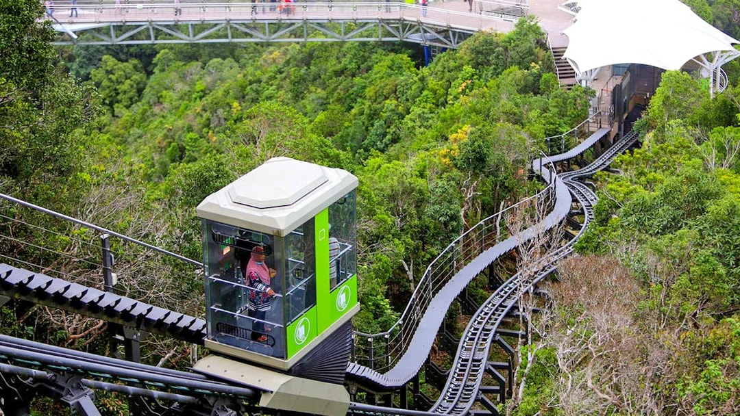 Langkawi Cable Car ascending through lush forest with a view of the sky bridge.