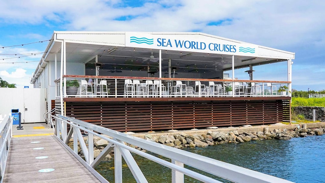 Pier leading to Sea World Cruises building with outdoor seating area.