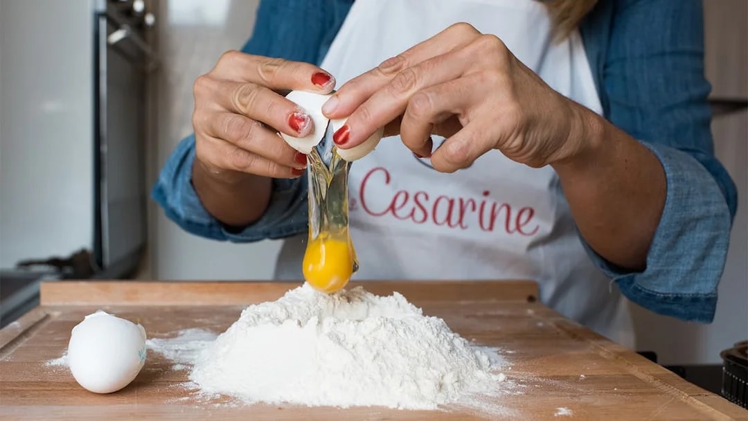 Cracking egg into flour during private cooking class in Bologna.