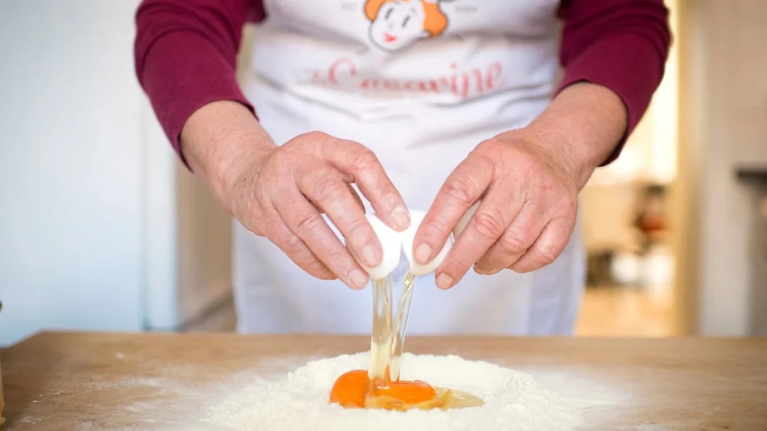 Cracking eggs into flour during a private cooking class in Rome.