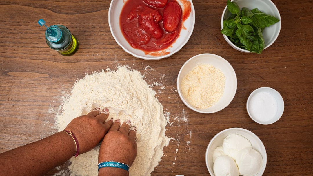 Hands kneading dough with ingredients for a private cooking class in Rome.