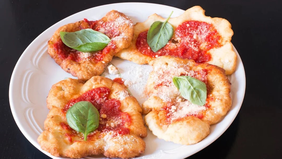 Fried pizza with tomato sauce and basil leaves, featured in a private cooking class in Rome.