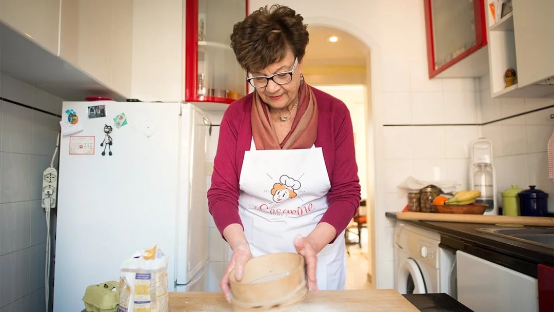 Woman sifting flour during a private cooking class in Rome kitchen.