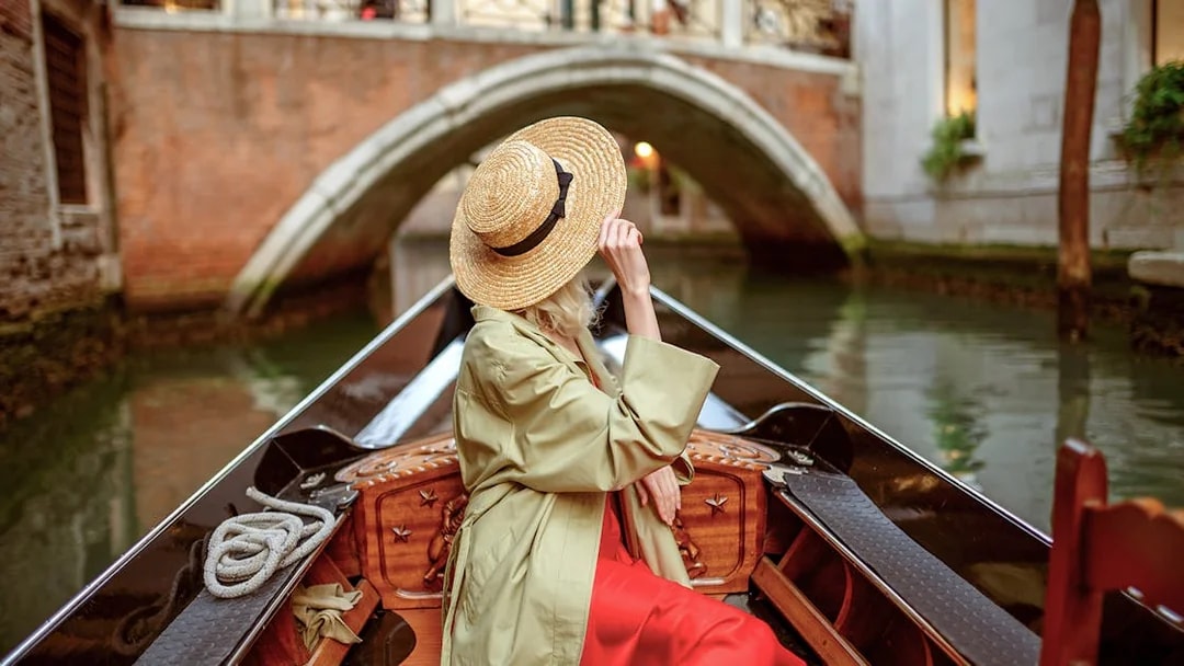 Tourist on gondola ride under bridge in Venice canal.