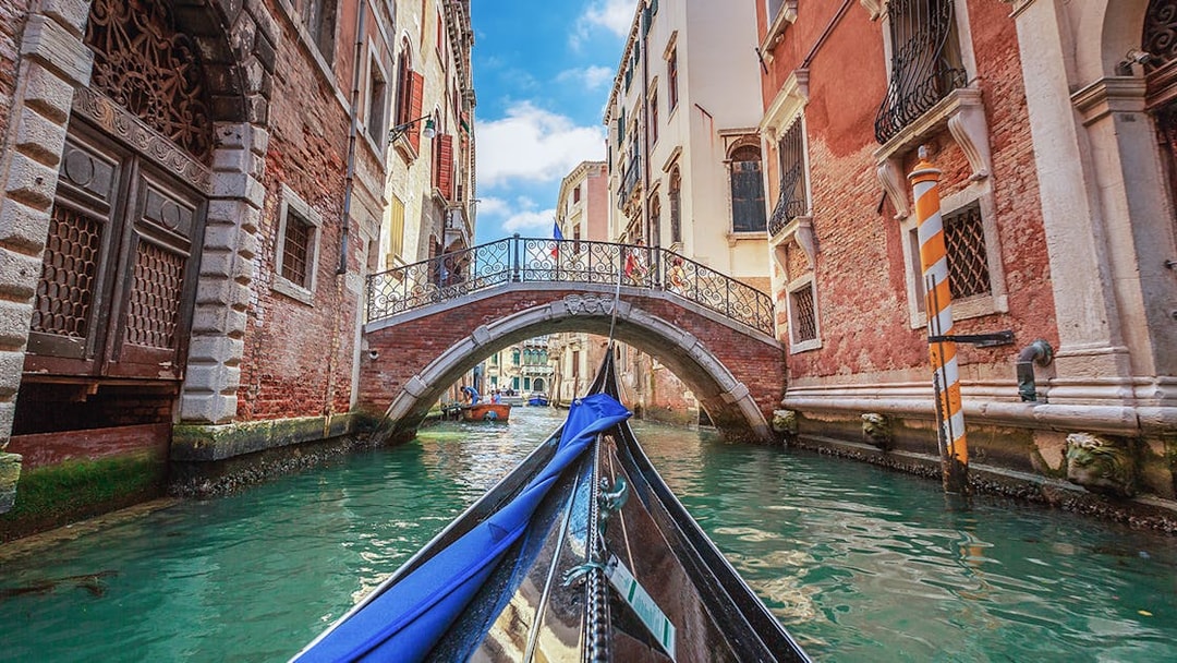 Gondola gliding under a stone bridge in Venice canal.