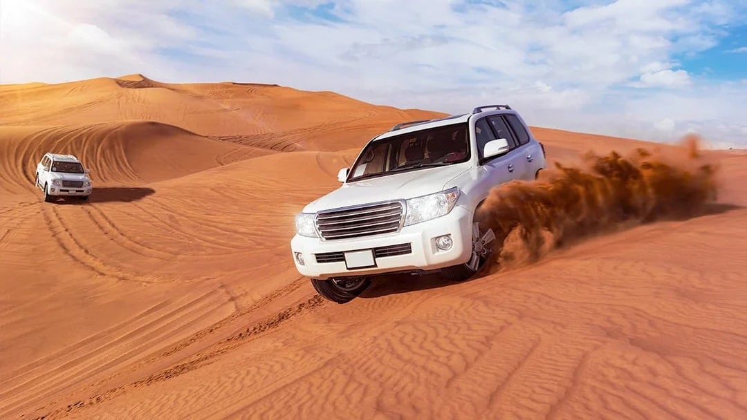 SUVs driving through sand dunes on a desert safari in Dubai.