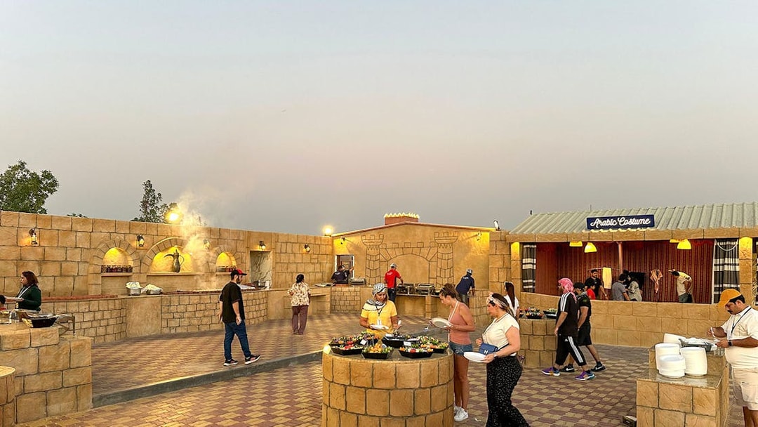 Guests enjoying buffet at an evening desert safari camp with Arabic decor.