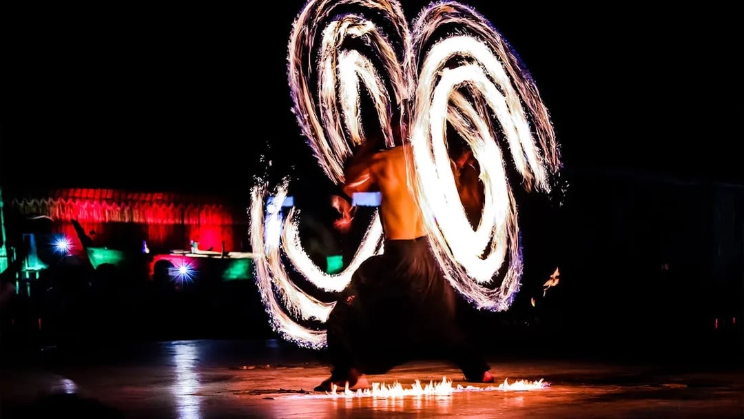Fire dancer performing at night during Dubai desert safari tour.