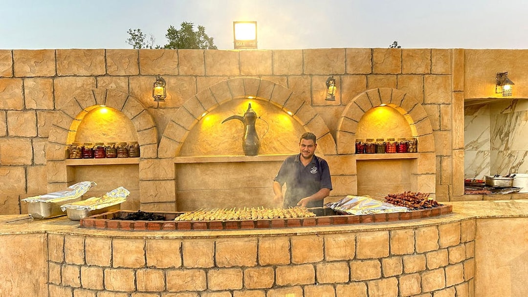 Grill chef preparing skewers at a desert safari barbecue station.