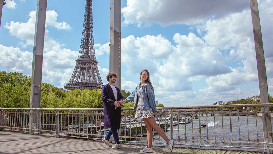 Couple posing on a bridge with the Eiffel Tower in the background, Paris.