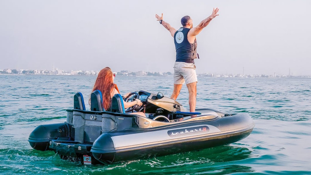 Tourists enjoying a self-drive boat ride on open water with city skyline in the background.