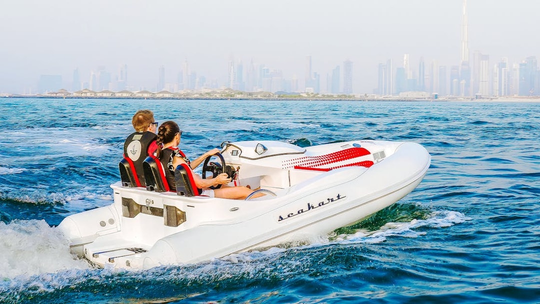 Tourists navigating a self-drive boat with a city skyline in the background.