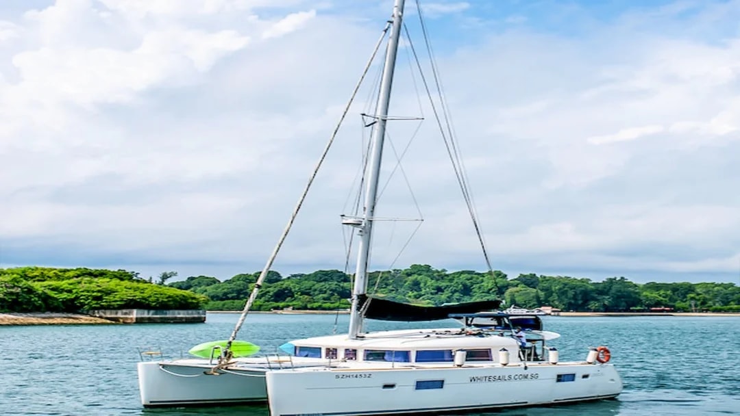 Private yacht anchored in a scenic bay with lush greenery in the background.