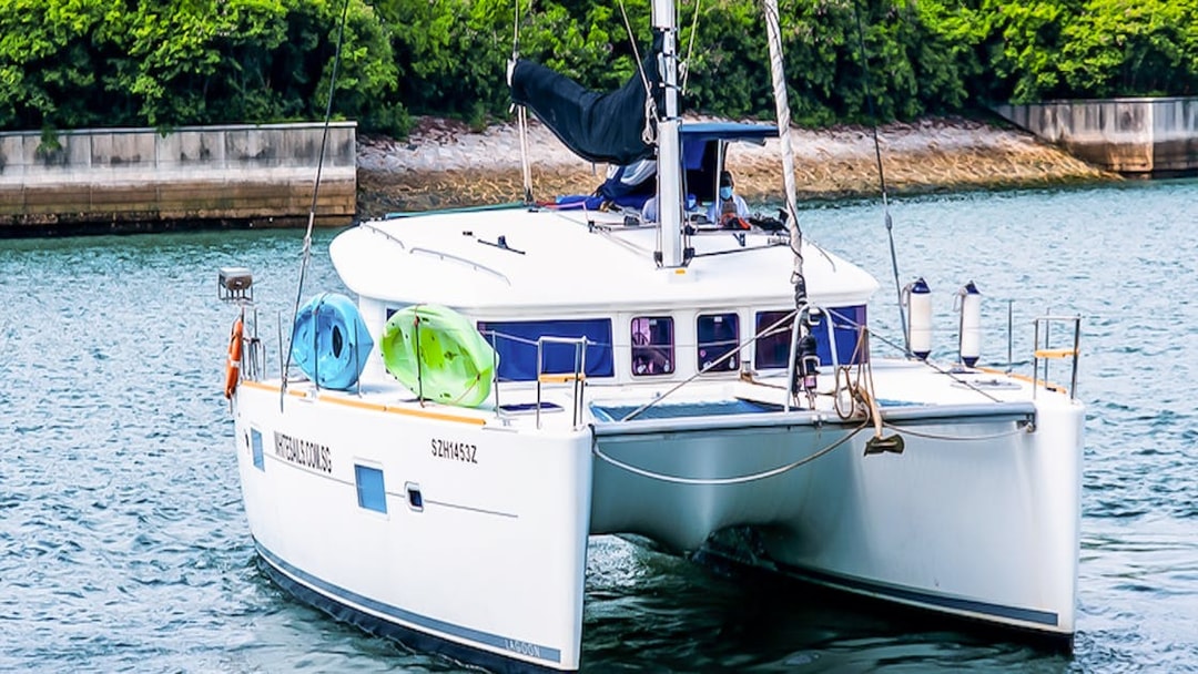 Private yacht SunRise sailing near lush shoreline with kayaks onboard.