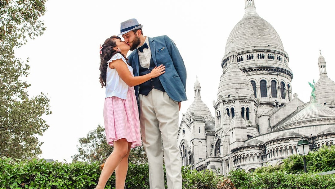 Couple kissing in front of Sacré-Cœur Basilica during Montmartre photoshoot experience.