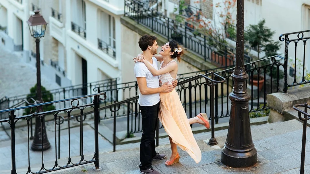 Couple embracing on Montmartre steps during professional photoshoot in Paris.