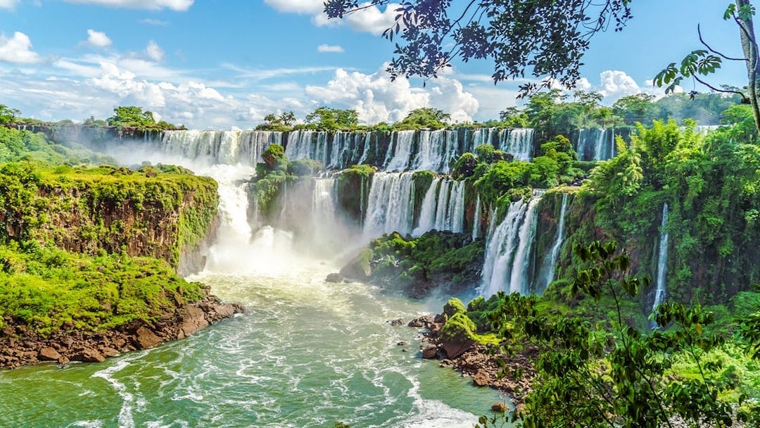 Iguazu Falls cascading over lush cliffs in Argentinian National Park.