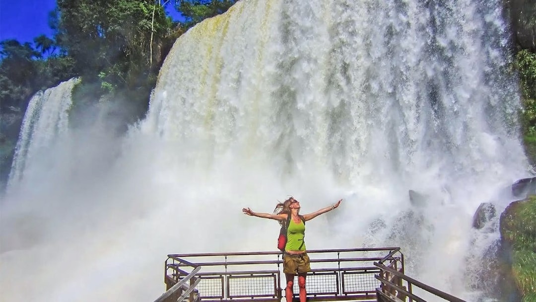 Visitor on a viewing platform at Iguazu Falls, Argentina, with cascading water in the background.