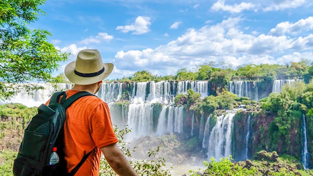 Traveler viewing Iguazu Falls in Argentina with lush greenery and cascading water.
