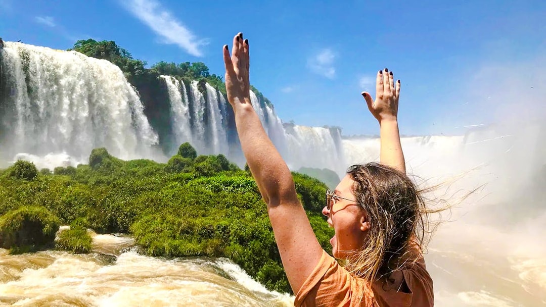 Visitor enjoying the view of Brazilian Falls with arms raised.
