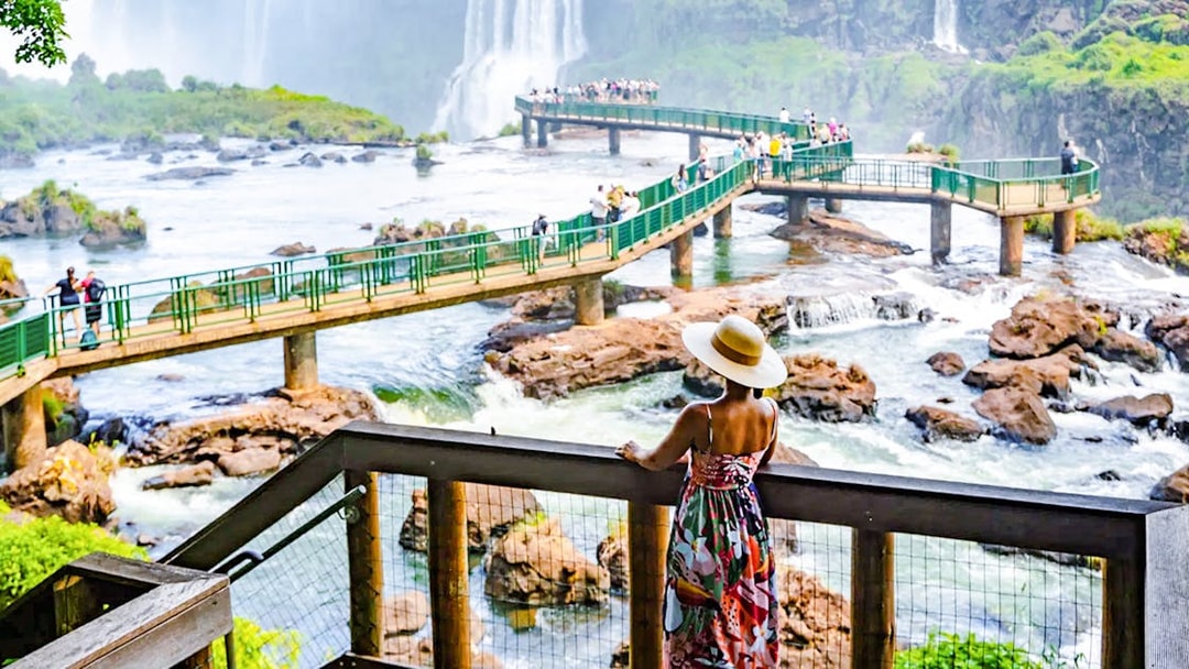 Visitor admiring Iguazu Falls from a viewing platform in Brazil.