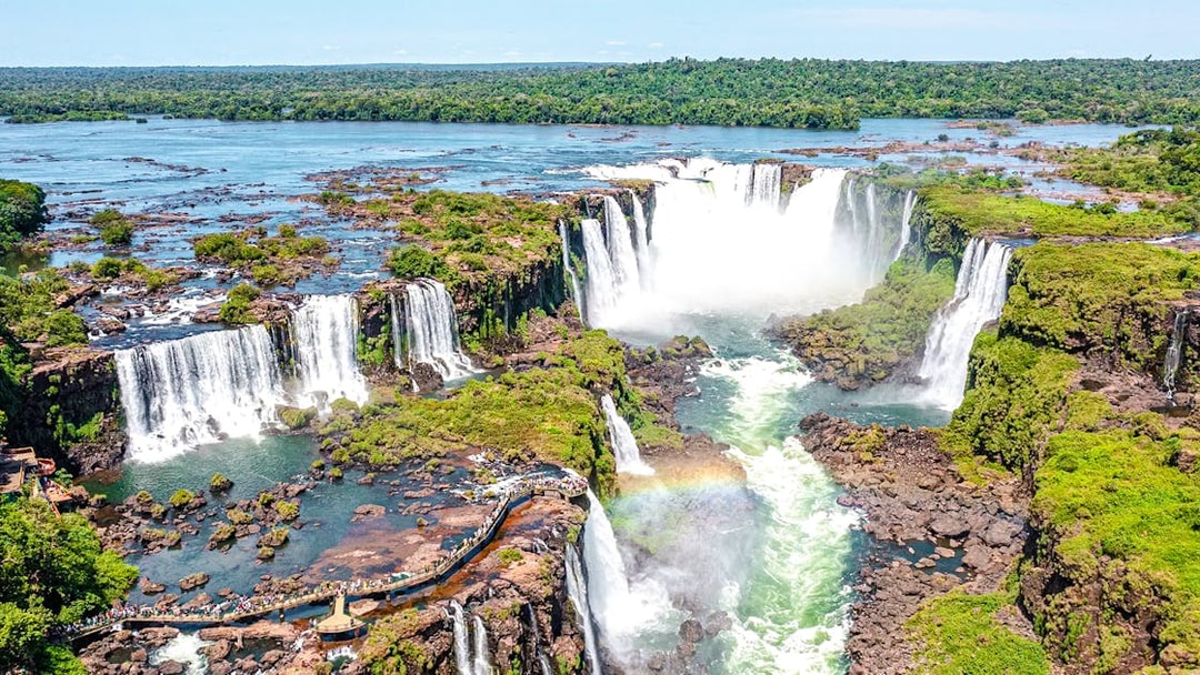 Aerial view of Iguazu Falls with lush greenery and a rainbow, Brazil.