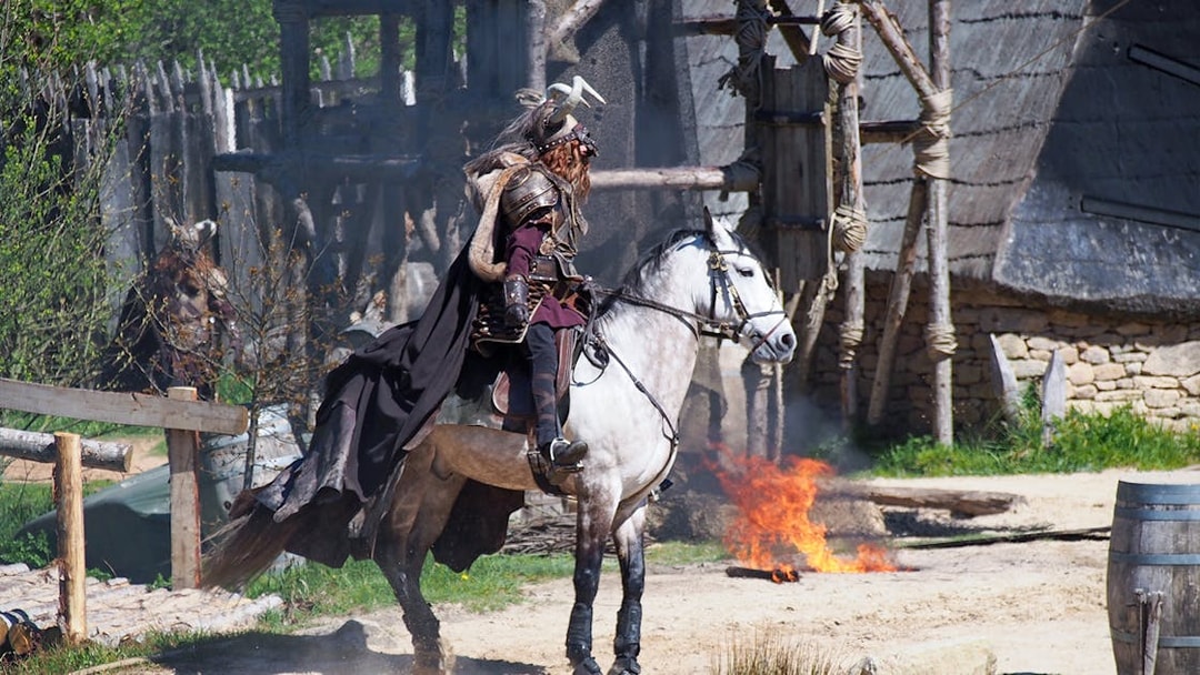 Medieval knight on horseback at Puy du Fou with fire in the background.