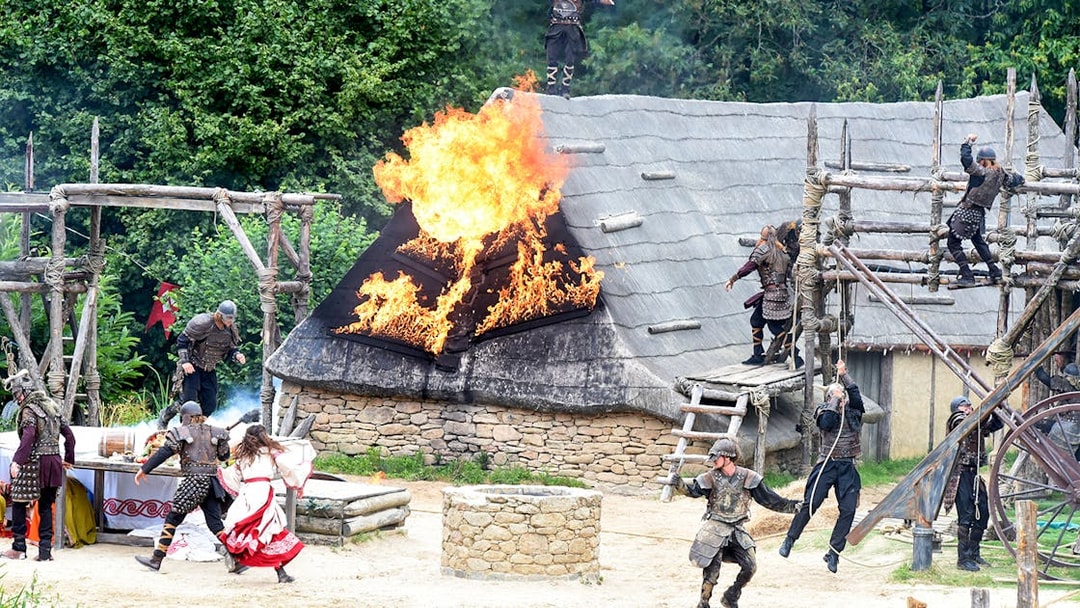 Viking reenactment with actors and burning roof at Puy du Fou, France.
