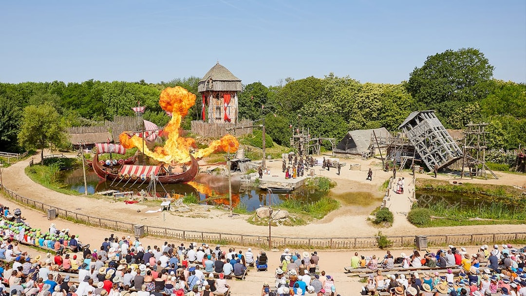Viking ship battle reenactment with fire effects at Puy du Fou Theme Park, France.