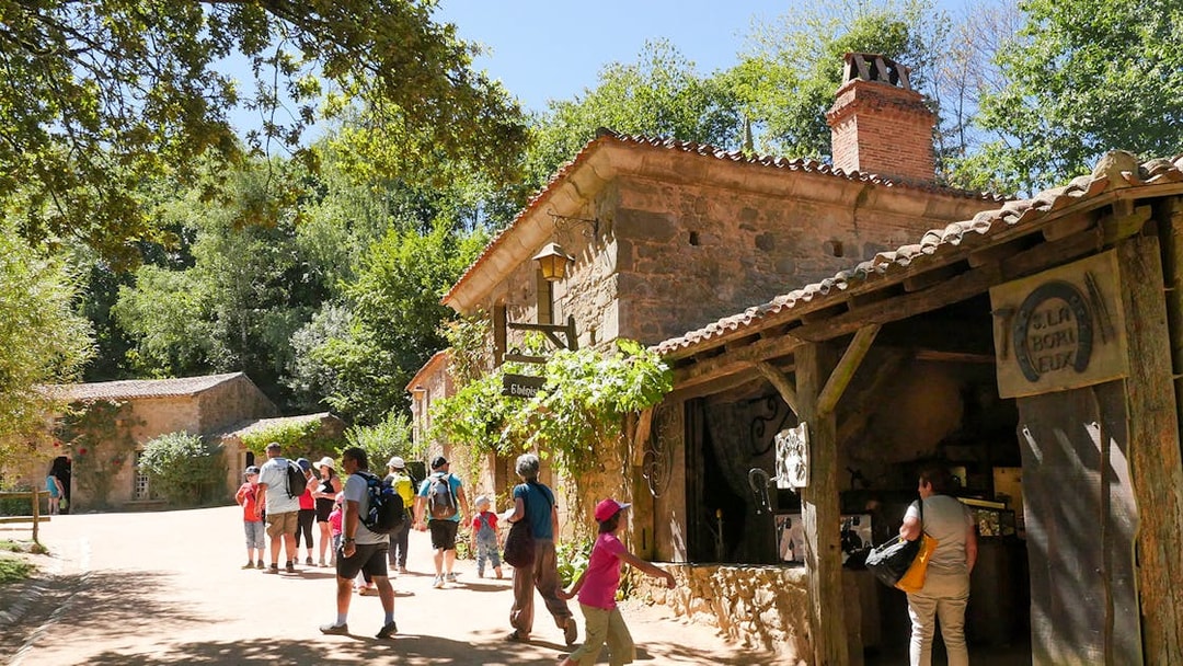 Visitors exploring rustic village at Puy du Fou Theme Park.
