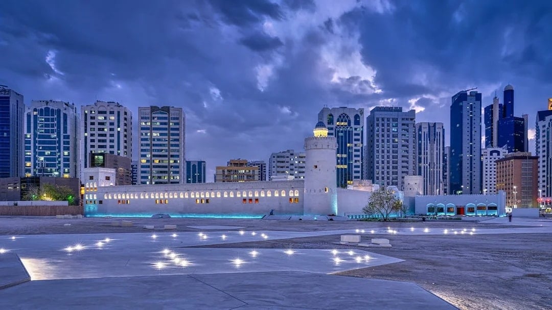 Qasr Al Hosn fortress in Abu Dhabi with modern skyline at dusk.