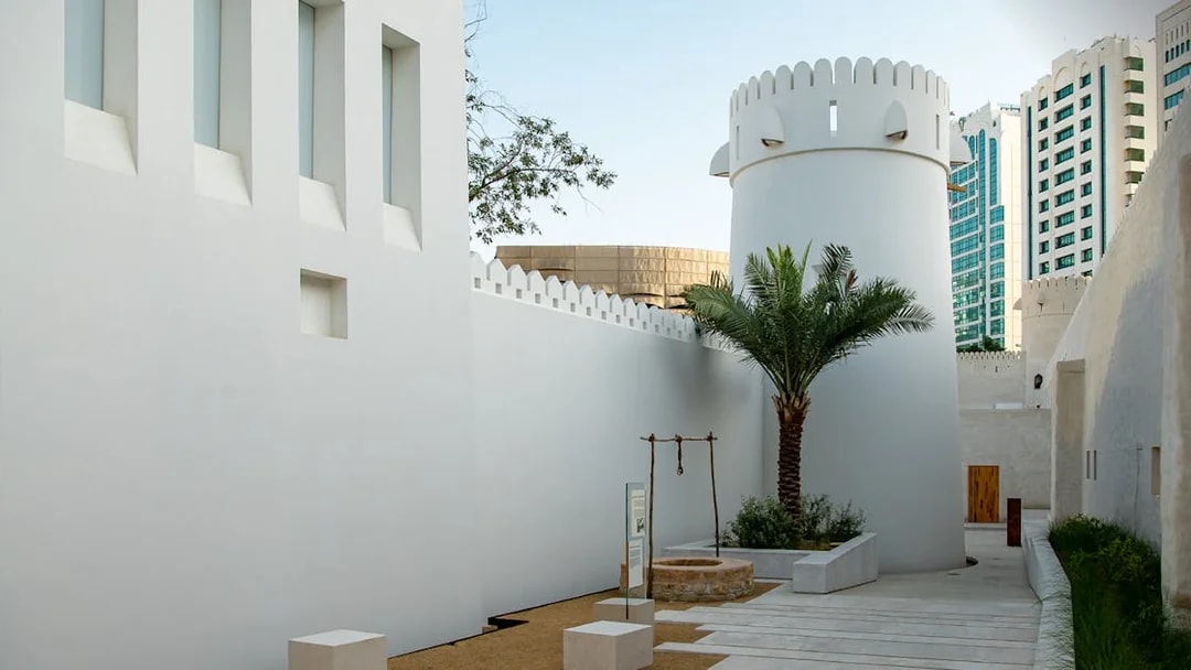 Qasr Al Hosn courtyard with historic tower and palm tree in Abu Dhabi.