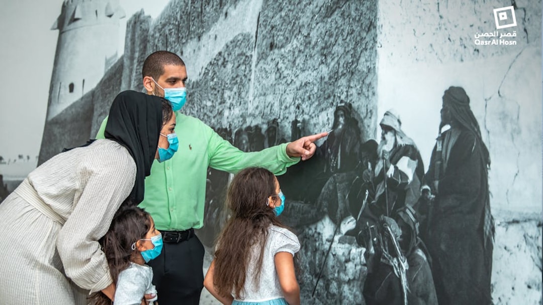 Family observing historical mural at Qasr Al Hosn, Abu Dhabi.