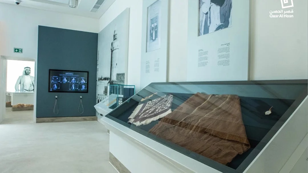 Exhibit of traditional garments and historical photos at Qasr Al Hosn museum, Abu Dhabi.